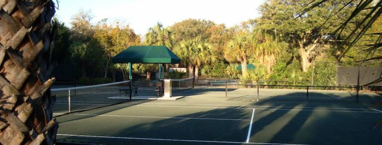 A serene tennis court surrounded by lush greenery, highlighted in the Visit Kiawah Island Guide for sports facilities.