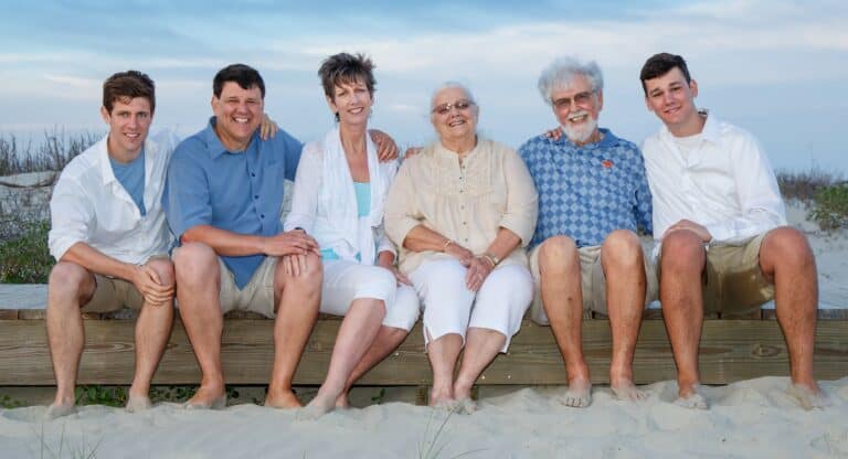 A happy family sitting closely together on a sandy beach at Kiawah Island, capturing a timeless family portrait.