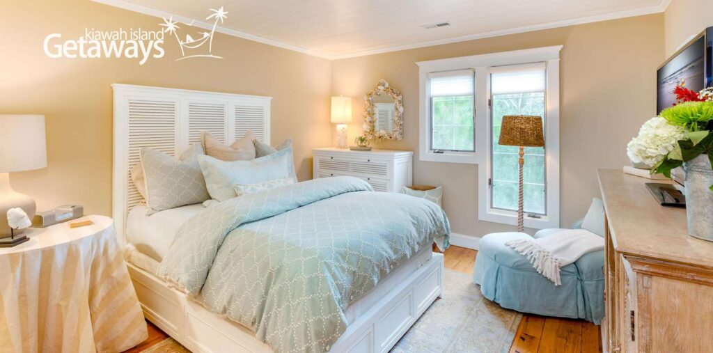 Light-filled bedroom with soft blue and cream tones at The Breeze at Seascape, curated by Kiawah Island Property Management.