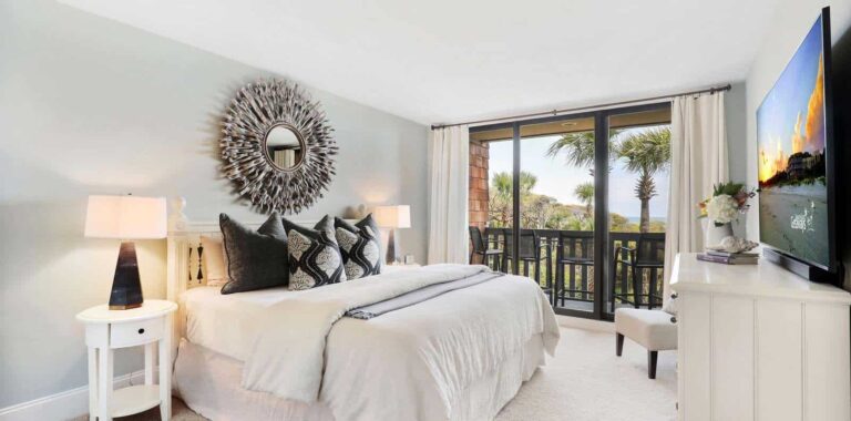 Sandpiper bedroom with plush bedding and balcony access, offering a serene retreat, overseen by Kiawah Island Property Management.