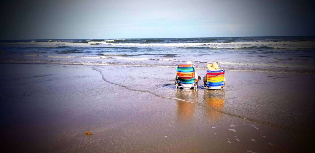 Colorful portable beach chairs with umbrellas set near the waves at Kiawah Island, offering a peaceful seaside retreat.