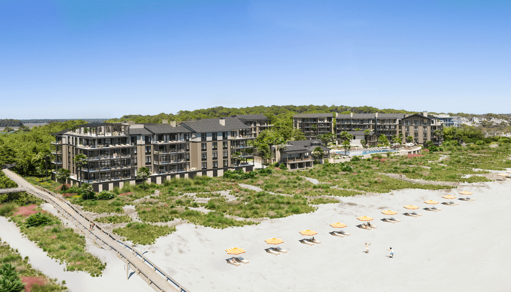 Aerial view of a beachfront property managed by Kiawah Cape Property Management, showcasing multiple buildings with sun loungers on the sand.